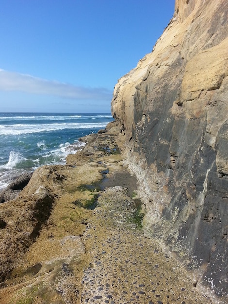 Photo scenic view of rocky mountain at sea shore against sky