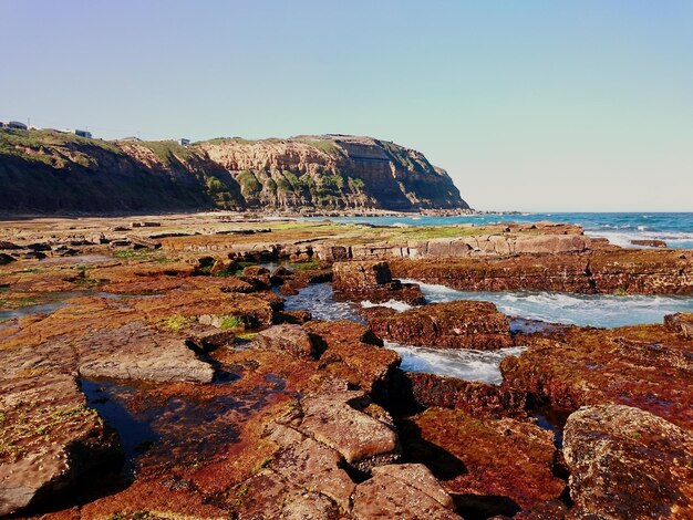 Scenic view of rocky shore against sky