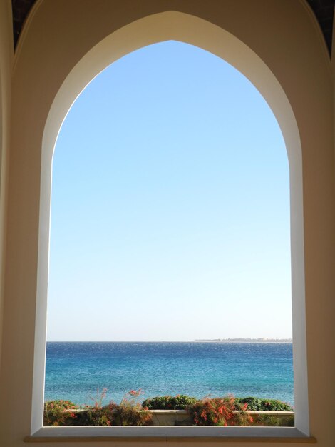 窓から見える澄んだ青い空の背景にある海の景色