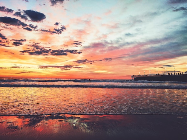 Photo scenic view of sea against cloudy sky during sunset