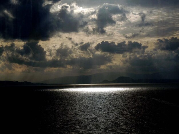 Photo scenic view of sea against cloudy sky during sunset