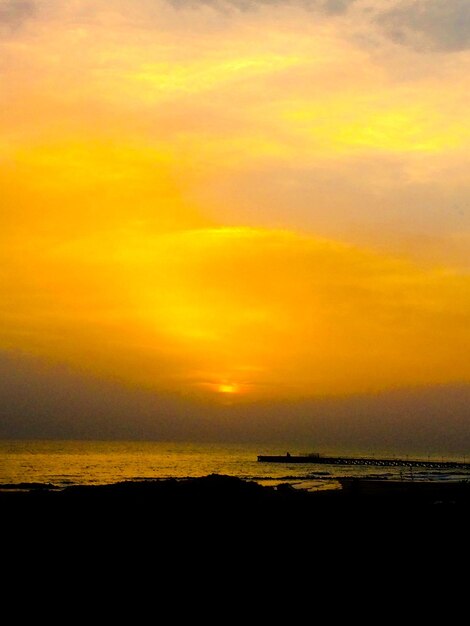 Scenic view of sea against cloudy sky at sunset