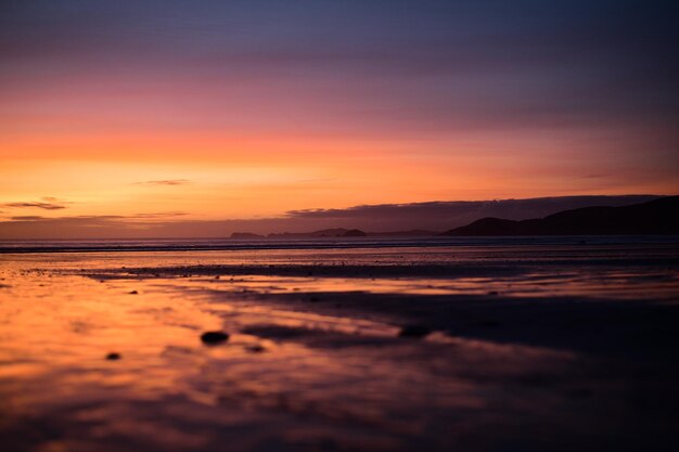 Photo scenic view of sea against dramatic sky during sunset