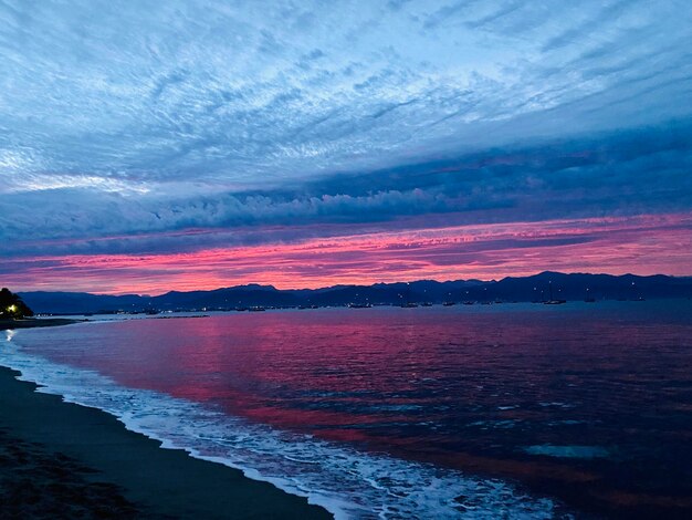 Scenic view of sea against dramatic sky during sunset