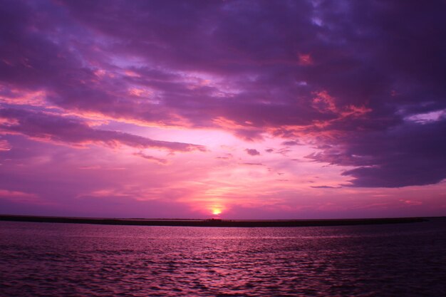 Photo scenic view of sea against dramatic sky during sunset