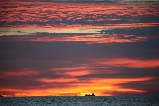 Photo scenic view of sea against dramatic sky during sunset