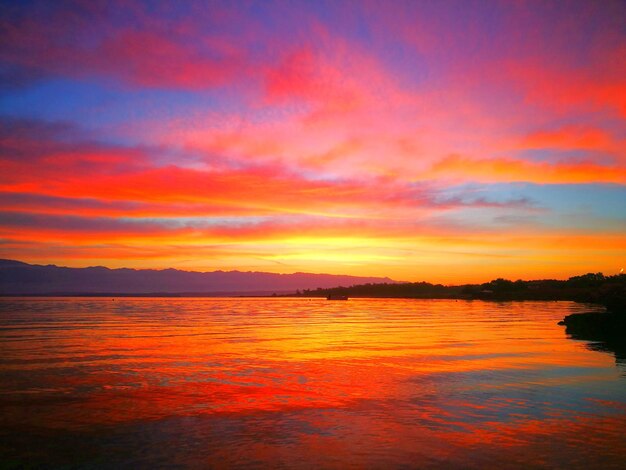 Scenic view of sea against dramatic sky during sunset