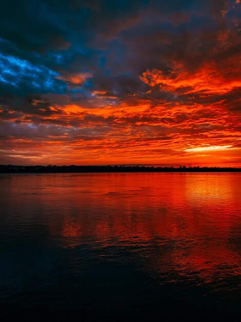 Photo scenic view of sea against dramatic sky during sunset