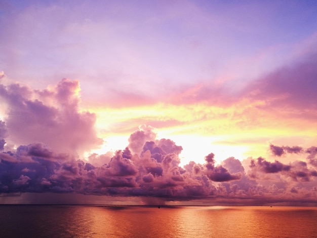 Photo scenic view of sea against dramatic sky during sunset