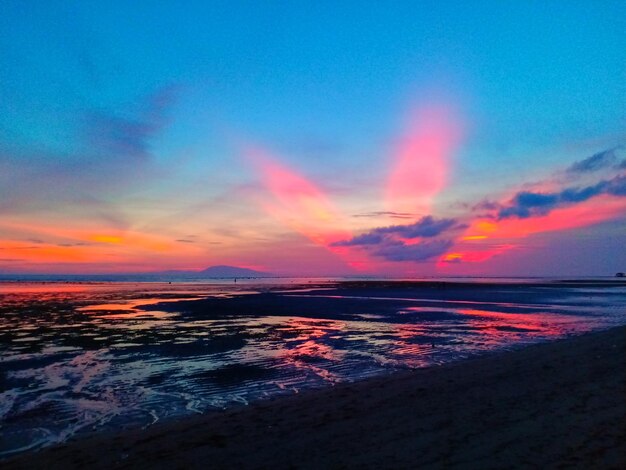 Scenic view of sea against dramatic sky during sunset