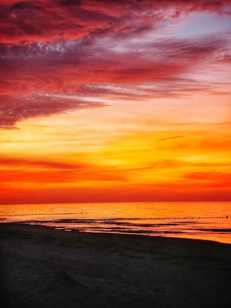 Photo scenic view of sea against dramatic sky during sunset