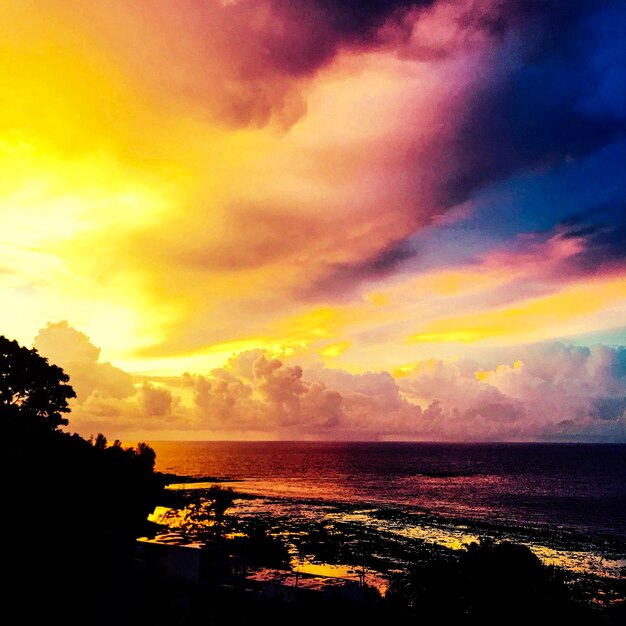 Scenic view of sea against dramatic sky during sunset