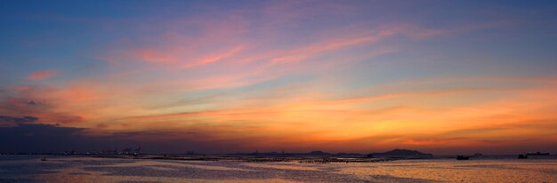 Photo scenic view of sea against dramatic sky during sunset