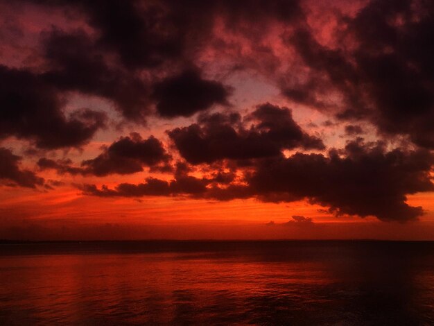 Photo scenic view of sea against dramatic sky during sunset