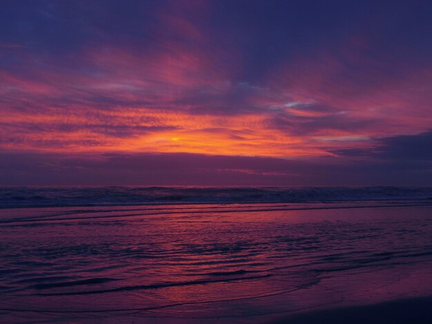 Photo scenic view of sea against dramatic sky during sunset