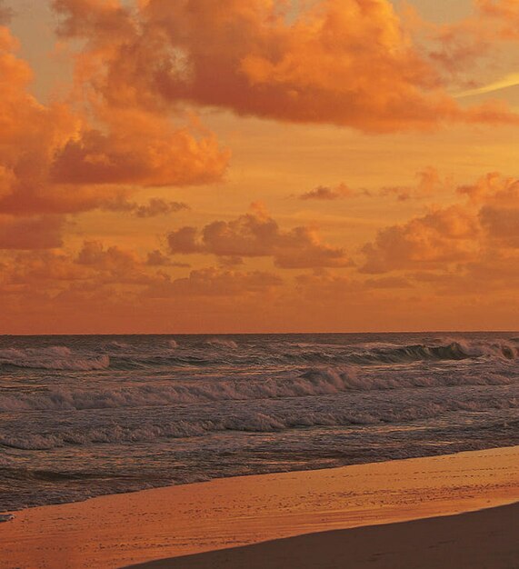 Scenic view of sea against dramatic sky during sunset