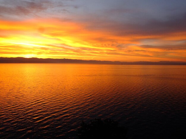 Scenic view of sea against dramatic sky during sunset