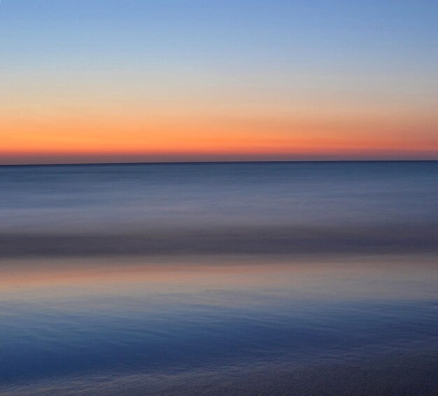 Photo scenic view of sea against sky during sunset