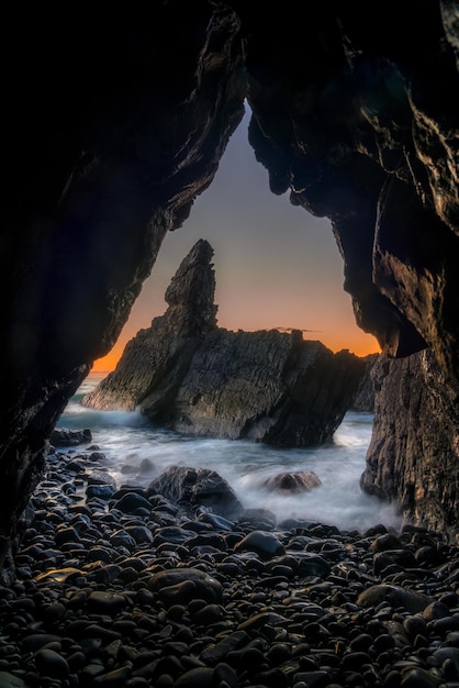 洞窟で撮影された日の出の空に照らされた海の景色