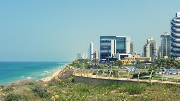 Scenic view of sea and buildings against clear blue sky