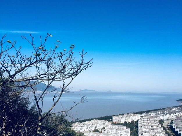 Scenic view of sea by buildings against clear blue sky