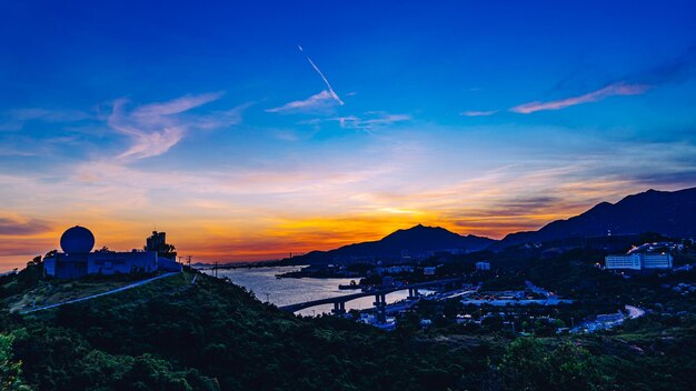 Scenic view of sea by buildings against sky during sunset