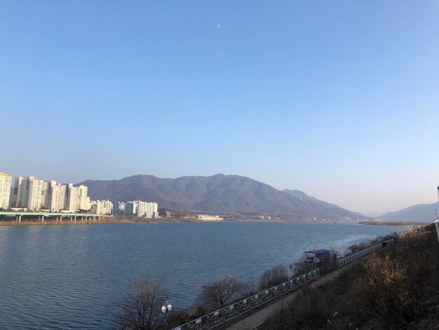 Scenic view of sea by city against clear blue sky