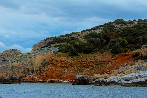 Scenic view of sea by mountain against sky