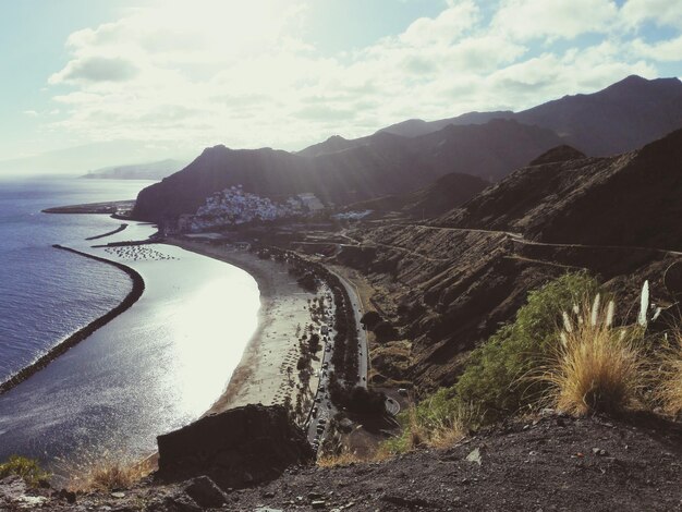 Scenic view of sea by mountains against sky