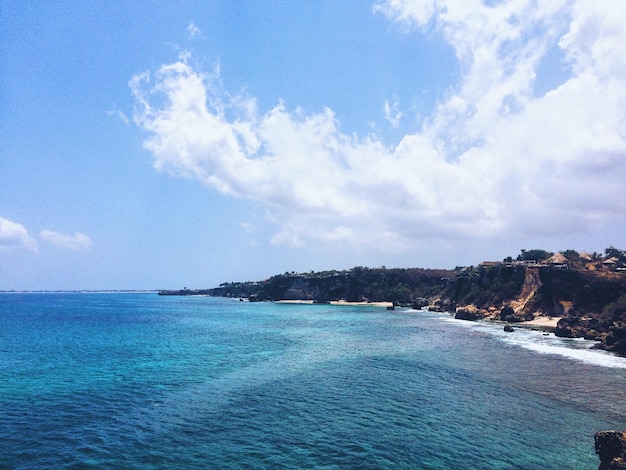 scenic view of sea by mountains against sky