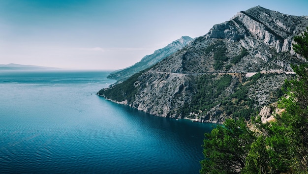 Photo scenic view of sea by rocky mountains against sky