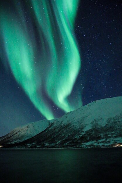 Photo scenic view of sea by snowcapped mountains against aurora polaris