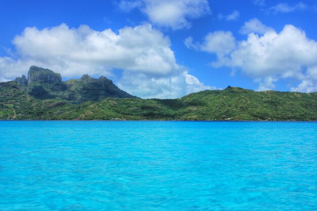 Scenic view of sea in front of mountains against cloudy sky