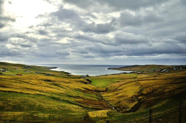 Photo scenic view of sea and landscape against cloudy sky