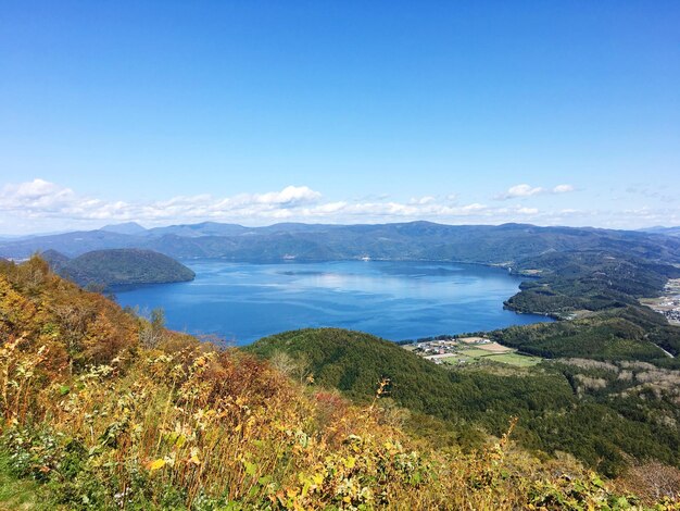 Photo scenic view of sea and mountains against blue sky