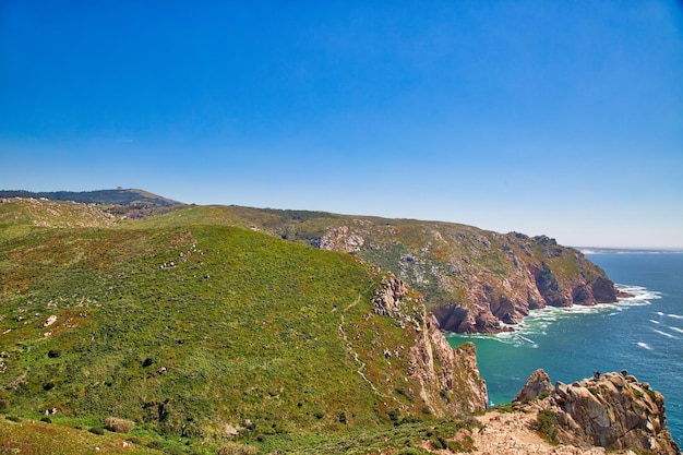 Scenic view of sea and mountains against clear blue sky