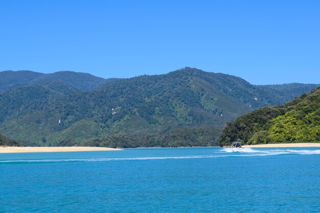 Scenic view of sea and mountains against clear blue sky