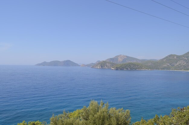 Scenic view of sea and mountains against clear blue sky