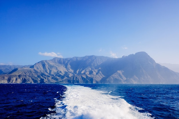 Scenic view of sea and mountains against clear blue sky