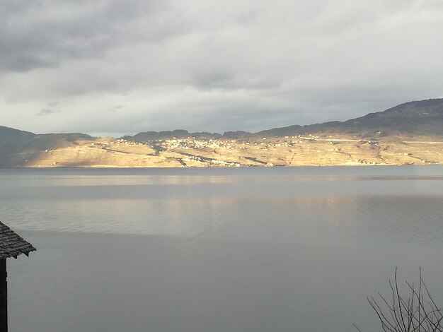 Scenic view of sea and mountains against cloudy sky