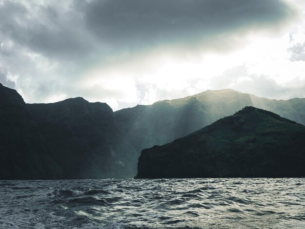 Photo scenic view of sea and mountains against sky