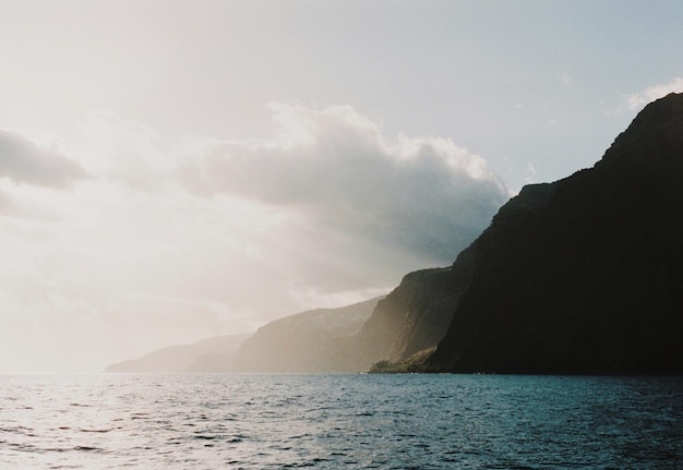 Photo scenic view of sea and mountains against sky