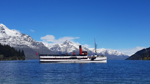 Scenic view of sea and snowcapped mountains against blue sky