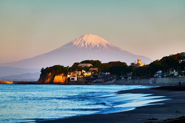 Foto la vista panoramica del mare e delle montagne innevate contro un cielo blu chiaro al mattino