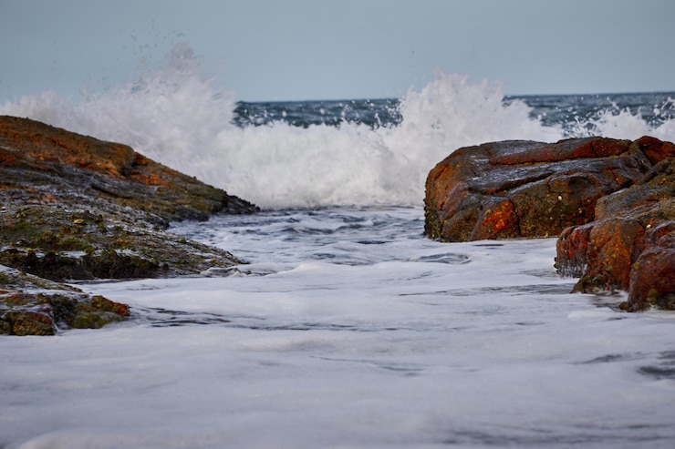 फोटो scenic view of sea waves splashing on rocks against sky