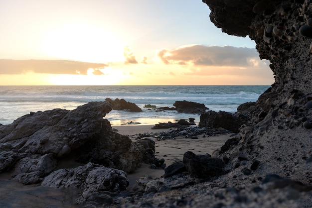 Photo scenic view of sealandscape at sunset time whit sun behind cloudsbackground