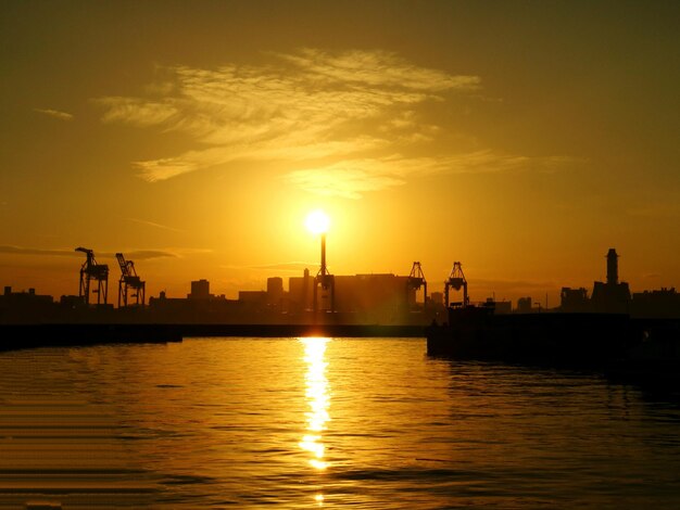 Scenic view of silhouette city by sea against sky during sunset