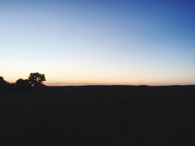 Scenic view of silhouette field against clear sky during sunset