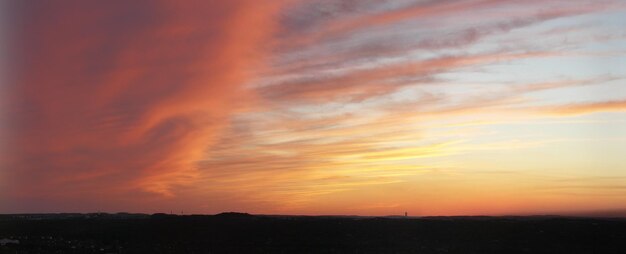 Scenic view of silhouette field against orange sky