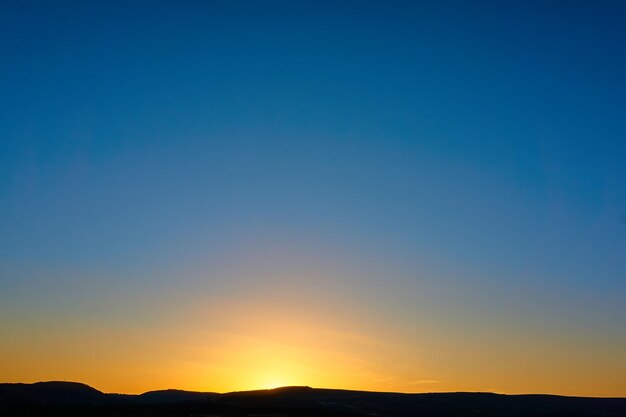 Scenic view of silhouette mountains against clear sky at sunset